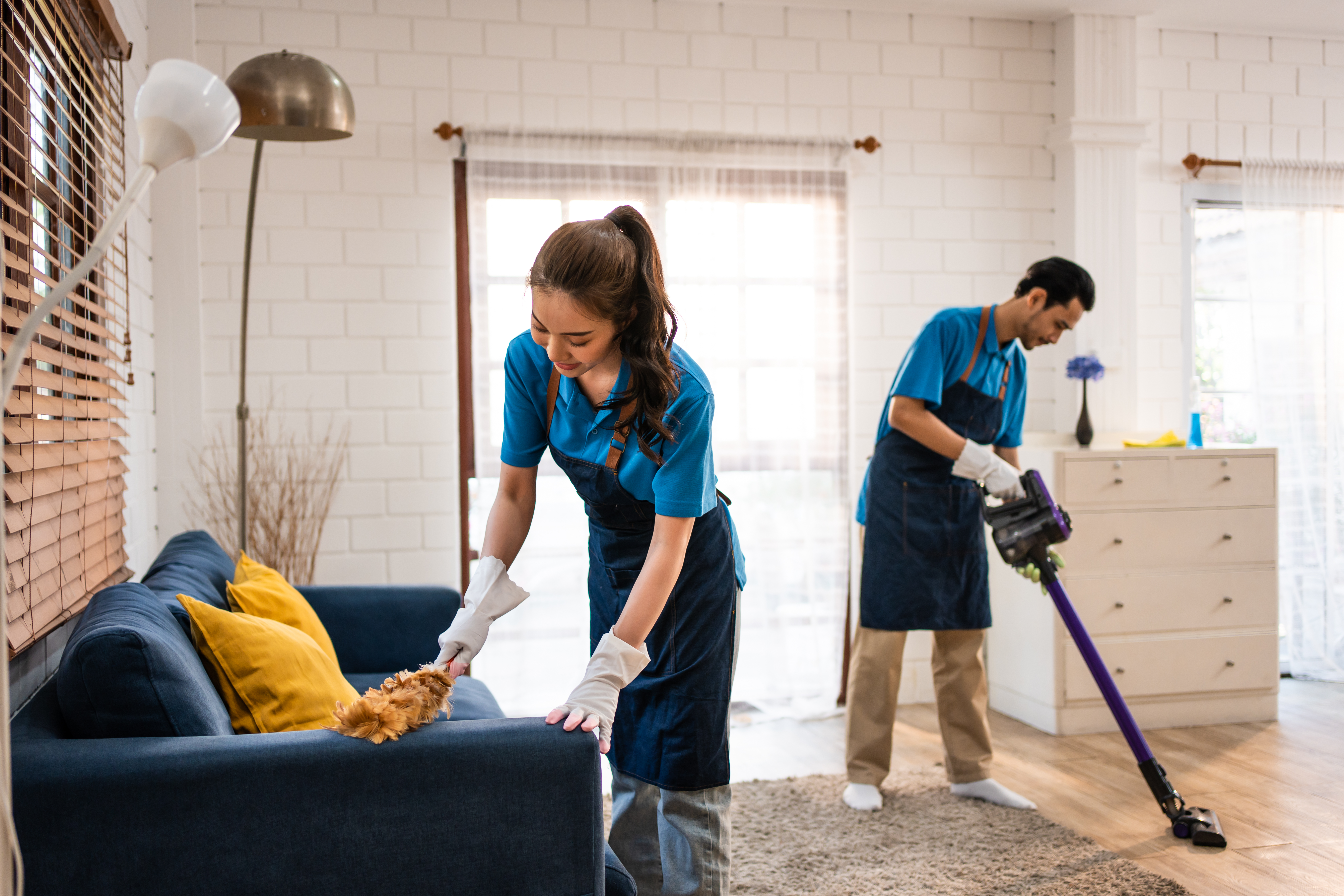 Cleaning team working in a Denver living room, vacuuming and dusting