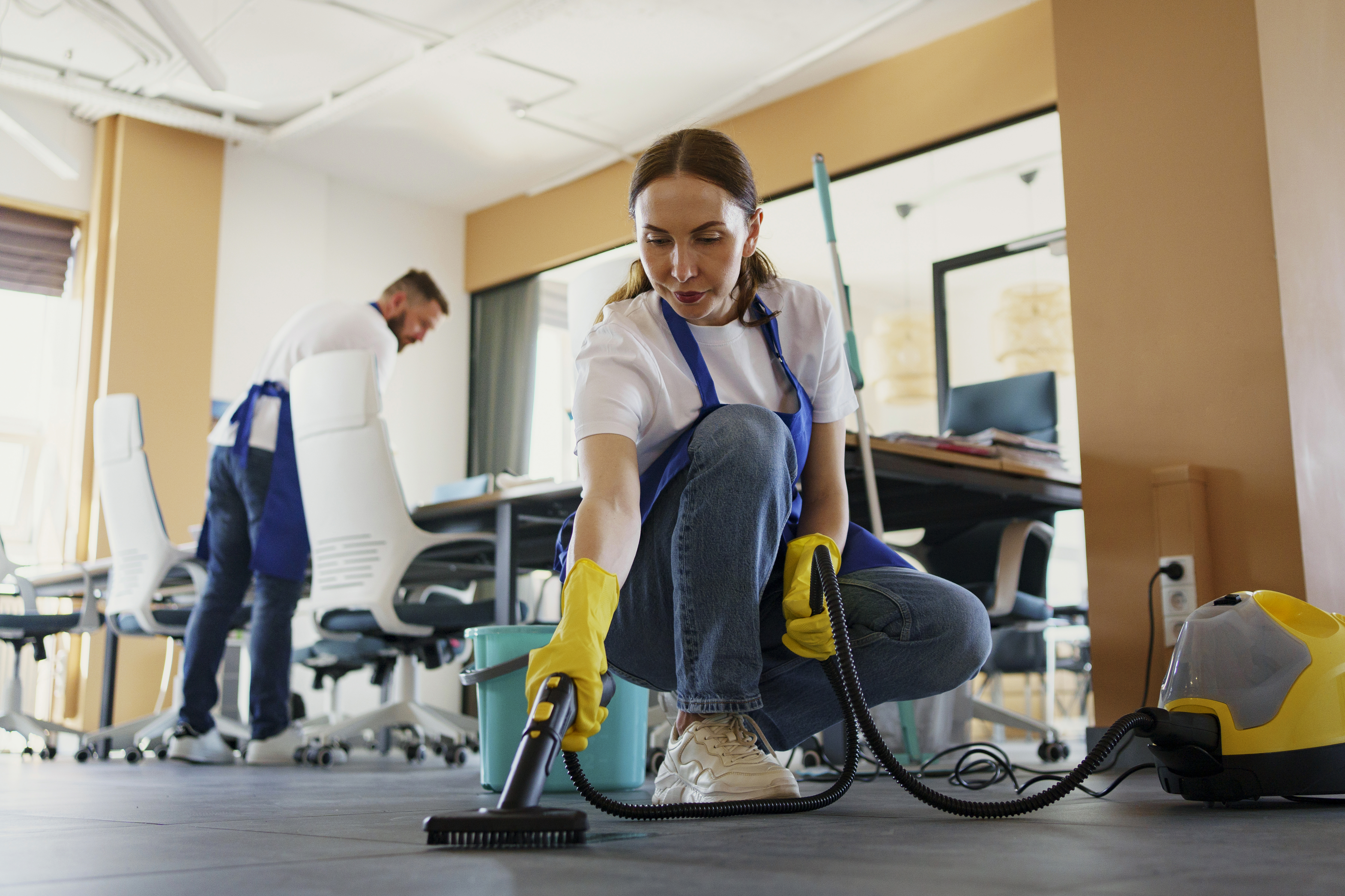 Cleaner vacuuming between desks in a Denver office after hours
